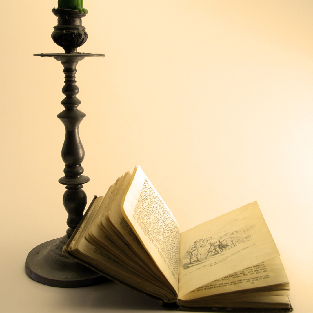 a photo of an open book with a silver candlestick to its left